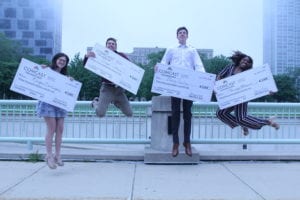 Young people holding large checks