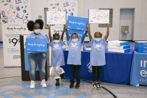 Four children wearing Internet Essentials shirts and holding signs.