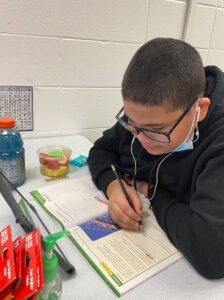 Young boy writing in workbook.