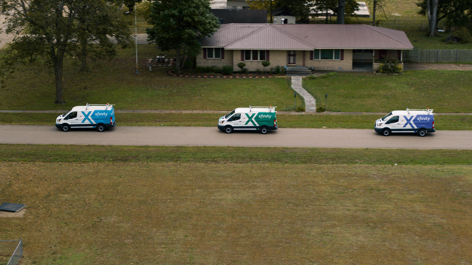 Three XFINITY vans line the front of a home.