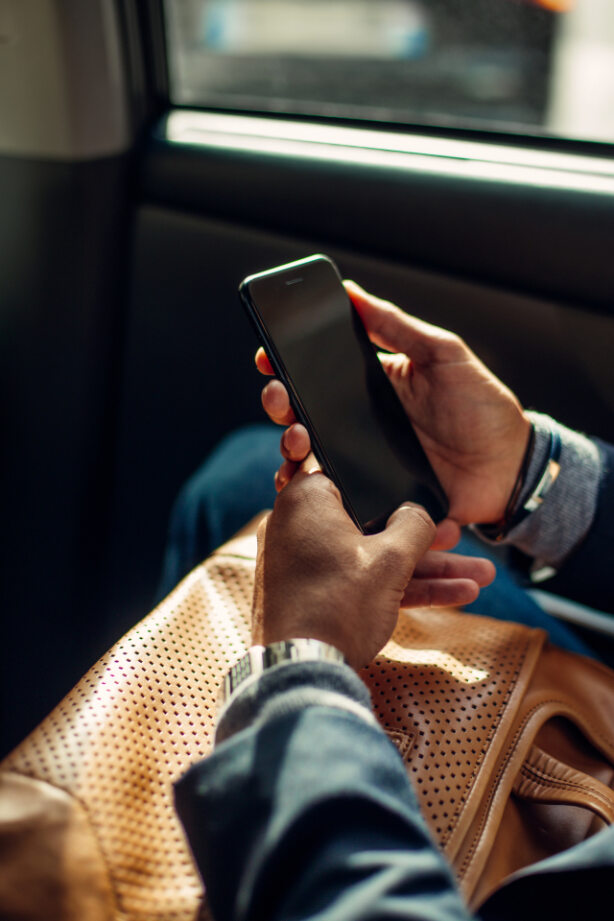 Businessman sitting in a car, using his mobile phone