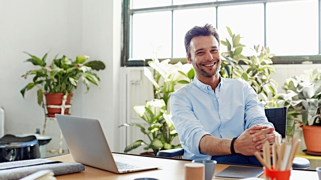 Portrait of smiling mid adult businessman sitting at desk in office